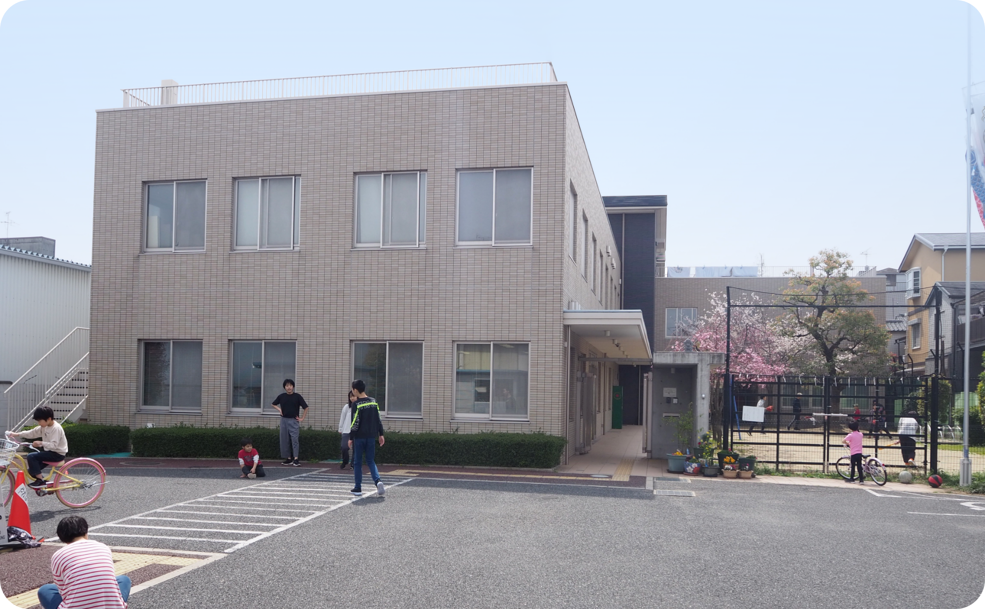 向陽学園の施設外観。建物前と隣接する園庭で子どもたちが遊んでいる。